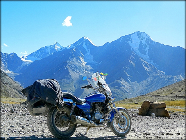 motorcycle in front of snow capped rocky peaks around the spiti valley india